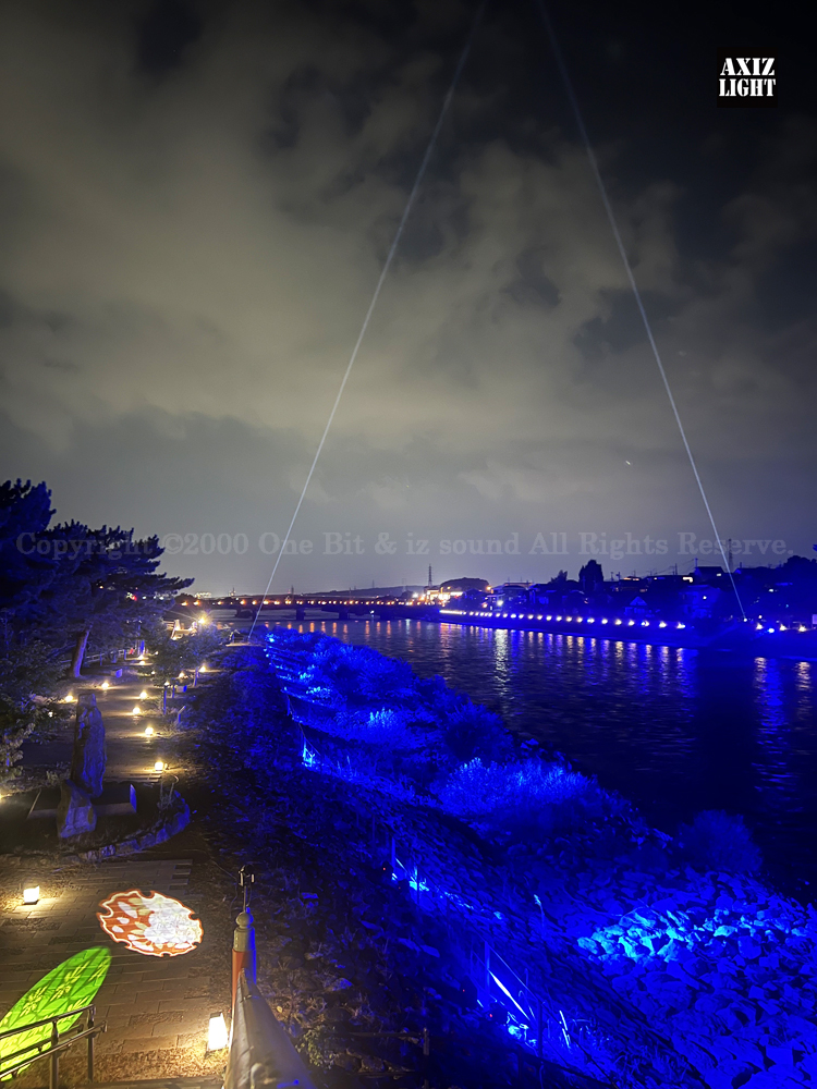 京の七夕 in Uji実施写真（4）宇治川天空演出！天空演出サーチライトによりひこ星と織り姫の出会いを演出！宇治の地において天空演出「天の川の出会い」を開催。一年に一度出会う天の川を夜空に描く、壮大な天空の七夕ショーを開催！“一年に一度、願いごとをする”という古くから伝わる七夕の節句の意義や云われを見つめ直し、その伝統を引き継ぎつつ、京都ならではの現代版・七夕まつりとして、京都各地で開催される「京の七夕」と融合して、宇治の風情を醸し出す情緒豊かな「京の七夕 in Uji」を開催いたします。※光りの演出＆ライトアップ＆イルミネーション＆プロジェクションランタン＆投影提灯＆手持ち提灯＆京の七夕。Lighting production and design by AXIZLight, and lighting designer KITATOSHI